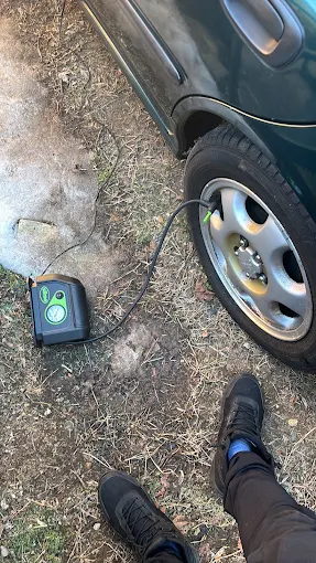 Inflating a flat tire with a portable air compressor at the roadside