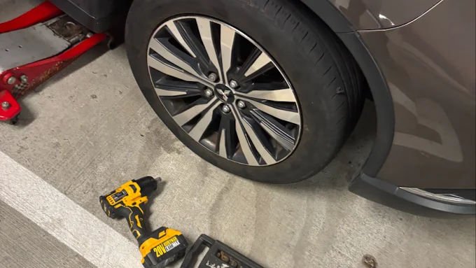 Roadside tire change in progress with impact wrench and jack